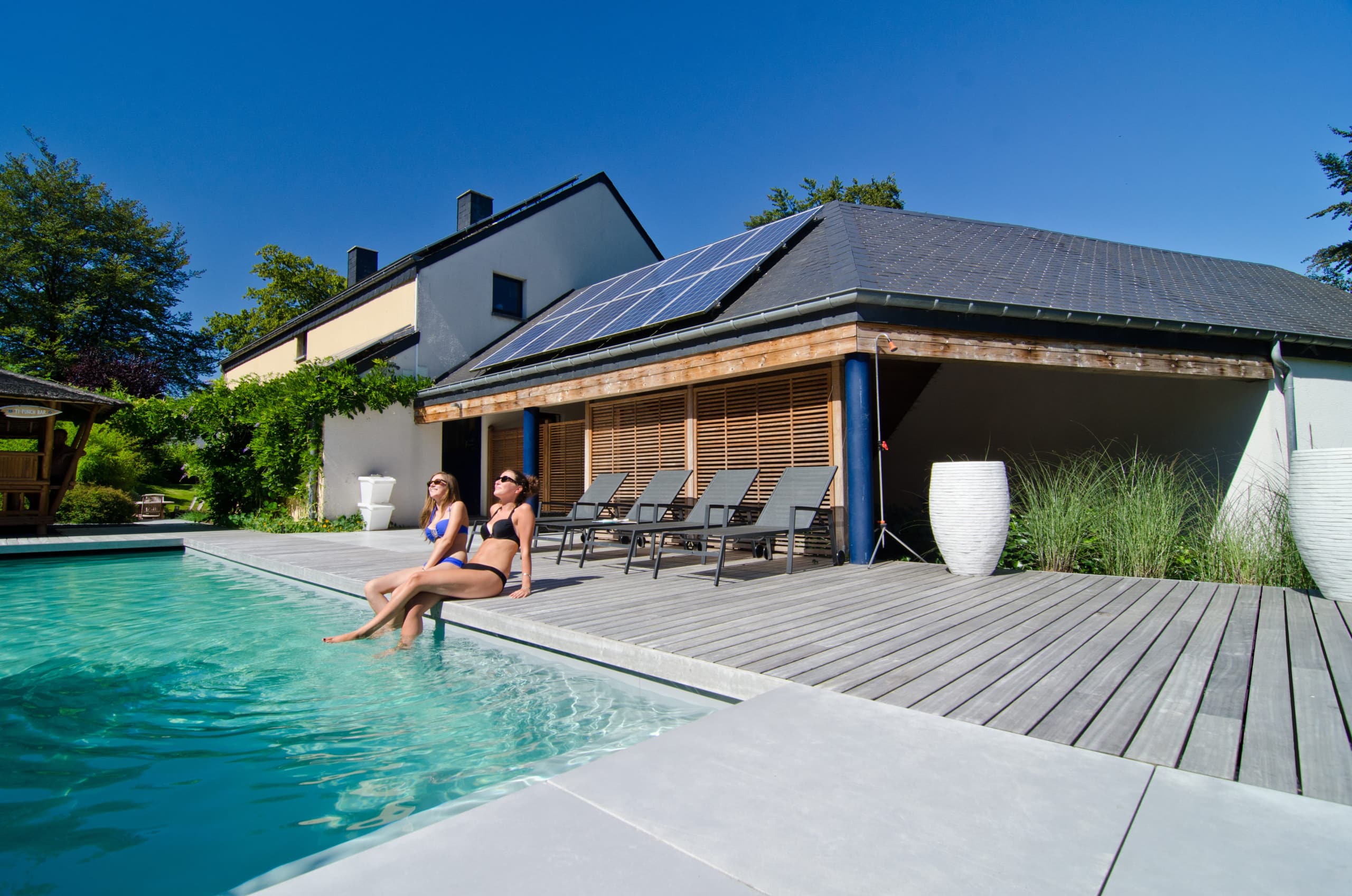 Women chilling next to a nice pool with a perfect wood padauk decking in belgium by Vetedy