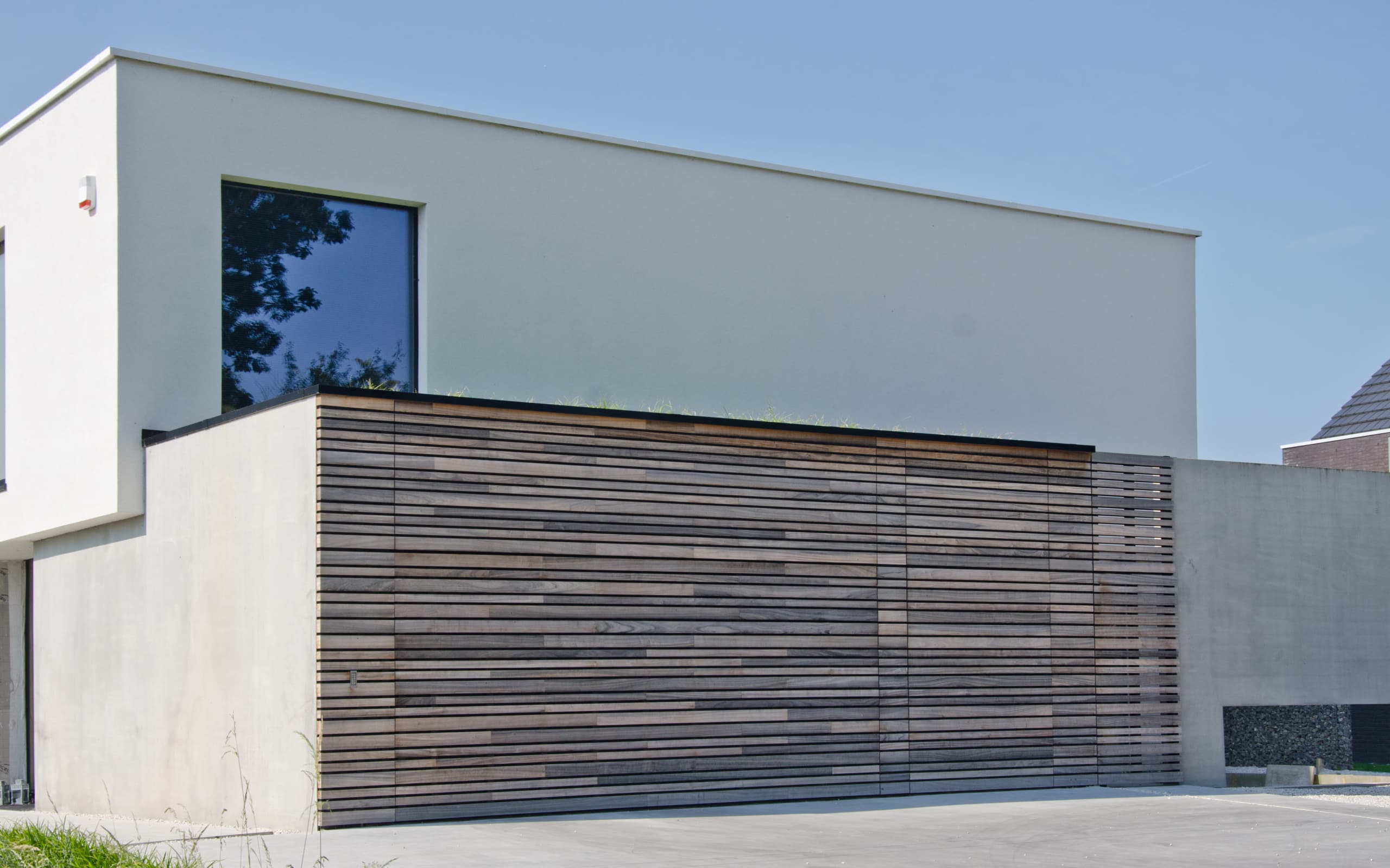 Bardage-en-bois-exotique-sur-une-porte-de-garage-Bardage en bois padouk electrical garage with techniclic wood cladding invisible system in Belgium by Vetedy