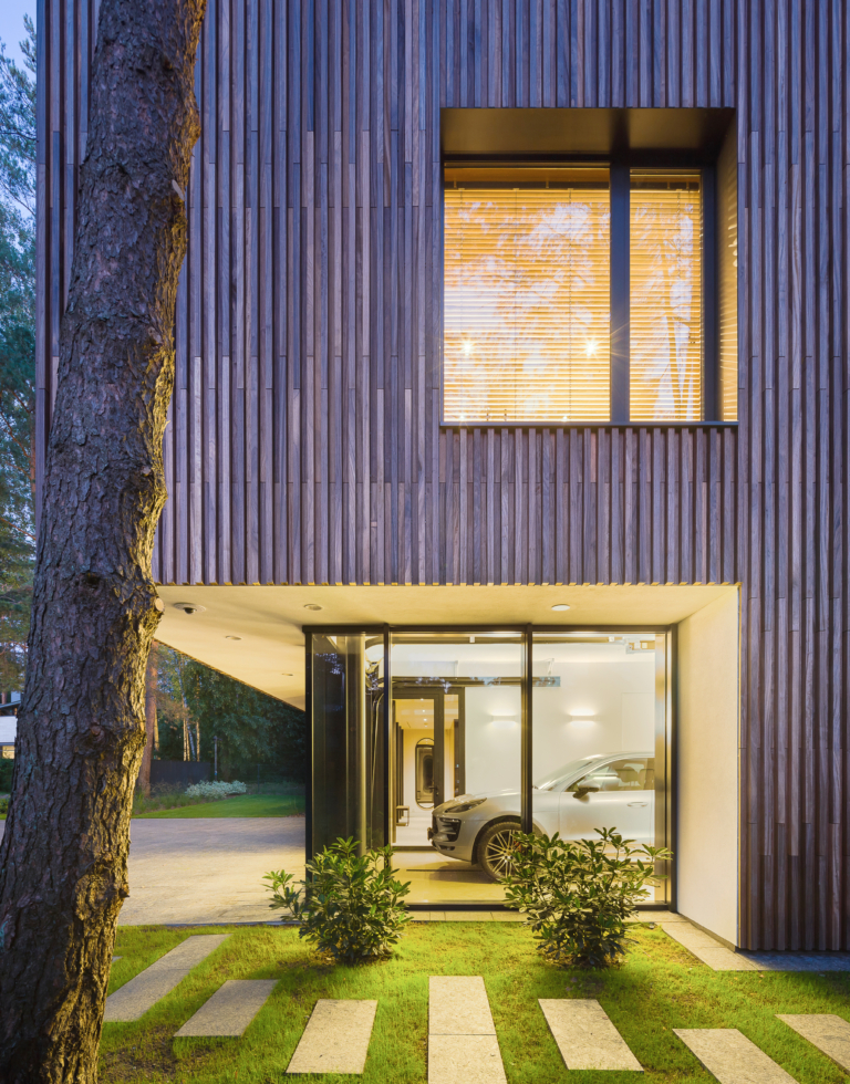voiture dans un garage d'une maison moderne avec une une façade en bois exotique en padouk