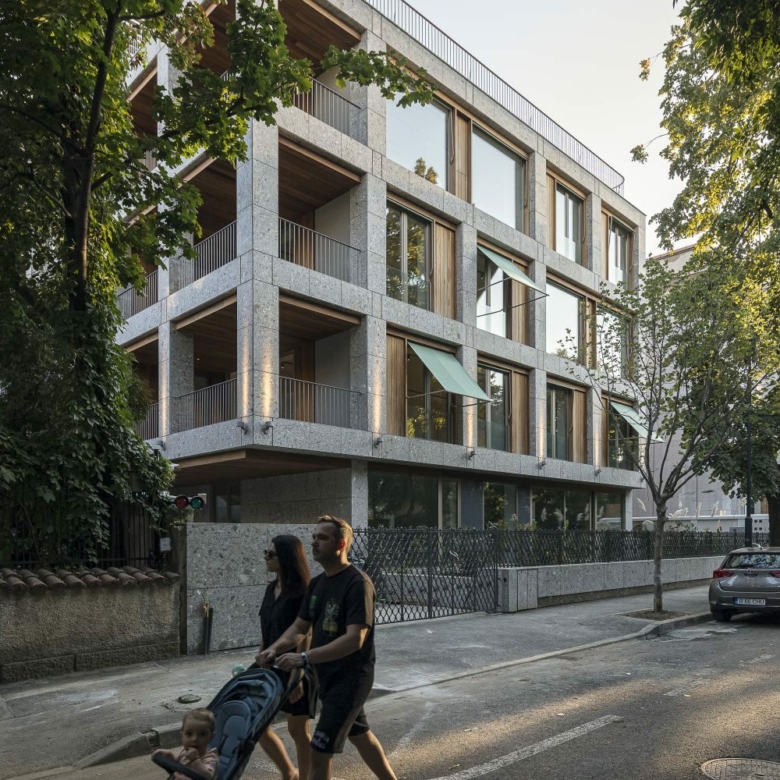 bloc d'appartement gris avec notre bardage en ayous techniclic dissimulé derrière des arbres