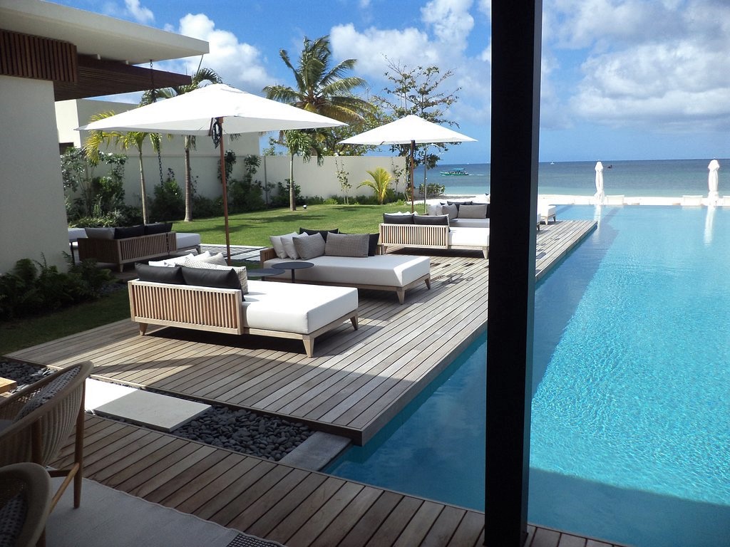 Salon extérieur sur terrasse Softline Ipé+ Teak Silversands Hotel Grenada au bord d'une piscine avec palmiers